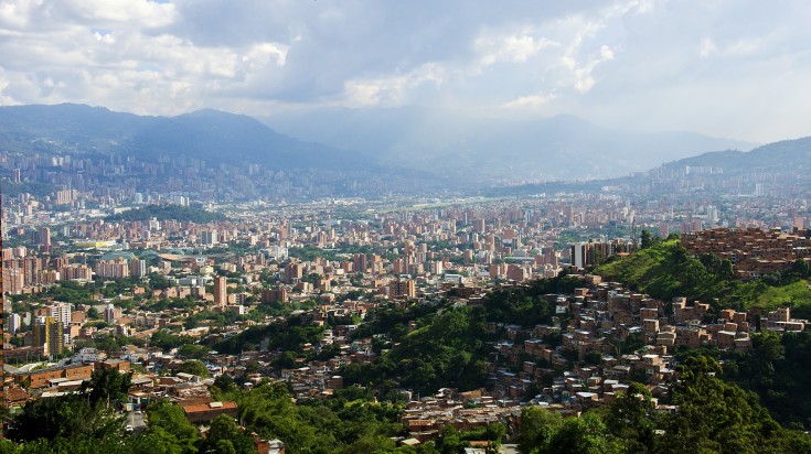 Vue panoramique de Medellín, ses immeubles et ses quartiers de briques à flanc de colline, dans la vallée entourée de montagnes vertes