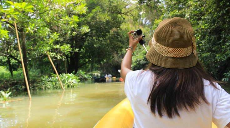 Voyageuse photographiant la forêt depuis un bateau sur une rivière du Costa Rica