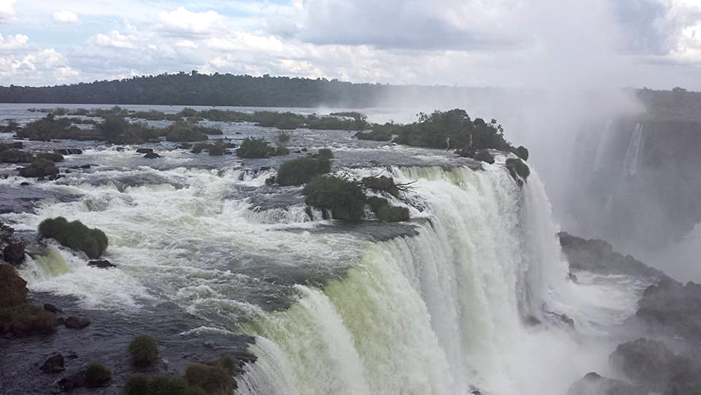 Chutes d’Iguazú se jetant entre des îlots boisés, la gorge du Diable noyée dans la brume en arrière-plan