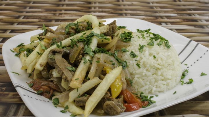 Assiette de lomo saltado, bœuf sauté aux oignons et tomates servi avec frites et riz blanc