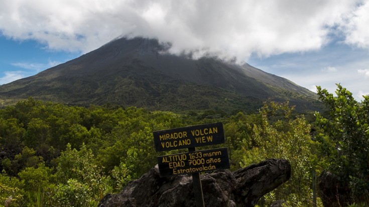 Panneau du belvédère du volcan Arenal, le sommet du volcan coiffé de nuages