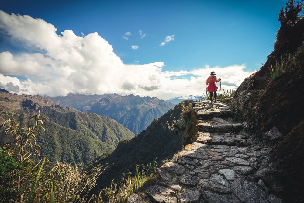 Randonneuse sur les marches de pierre du Chemin de l’Inca, face aux montagnes andines