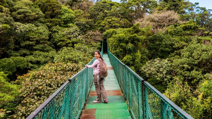 Randonneuse sur un pont suspendu au-dessus de la canopée de la forêt de nuages de Monteverde