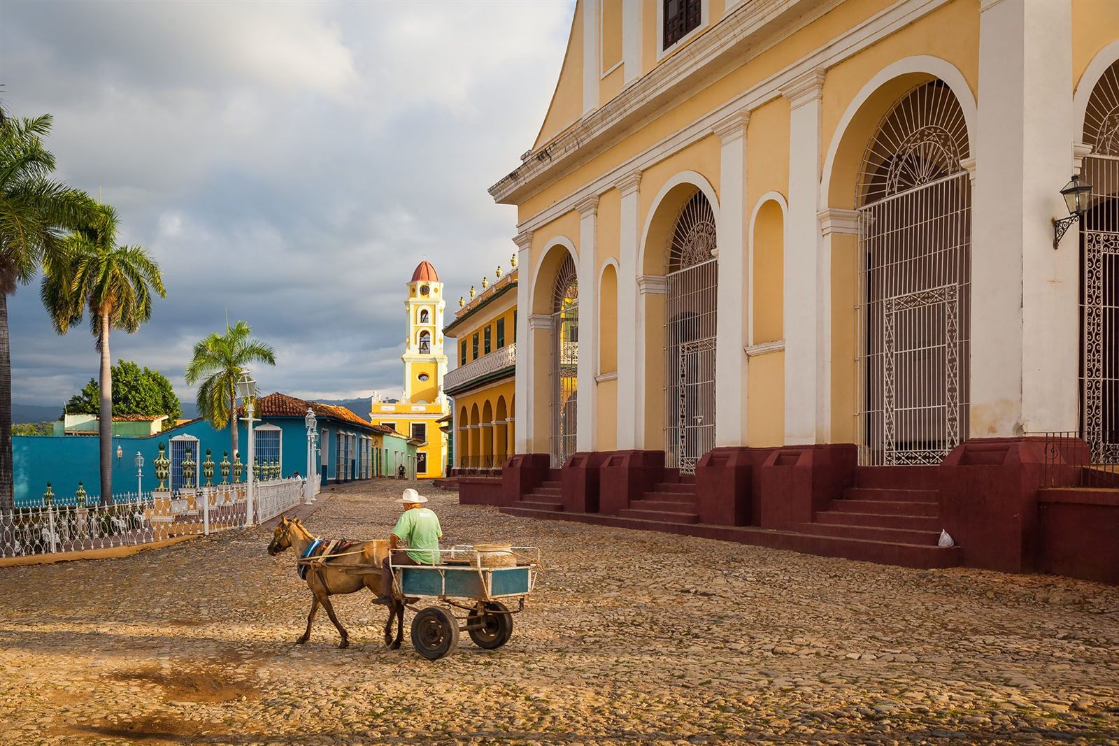 Place pavée du centre historique de Trinidad, à Cuba, avec une charrette à cheval et le clocher jaune de l’ancien couvent San Francisco