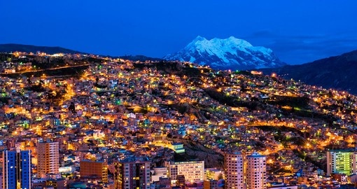 La Paz illuminée à la tombée de la nuit, avec le sommet enneigé de l’Illimani en arrière-plan