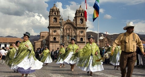Danseuses en costume traditionnel lors d’un défilé sur la Plaza de Armas de Cusco, devant une église coloniale