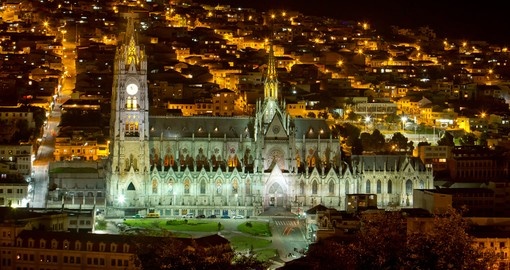 La basilique du Vœu national illuminée la nuit, au-dessus du centre historique de Quito
